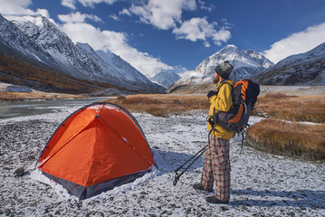 Hiker with backpack at camping in the mountains during springtime.