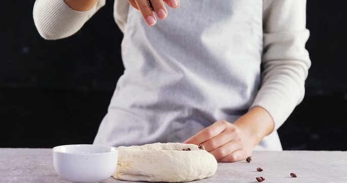 Woman adding chocolate chips into the dough 
