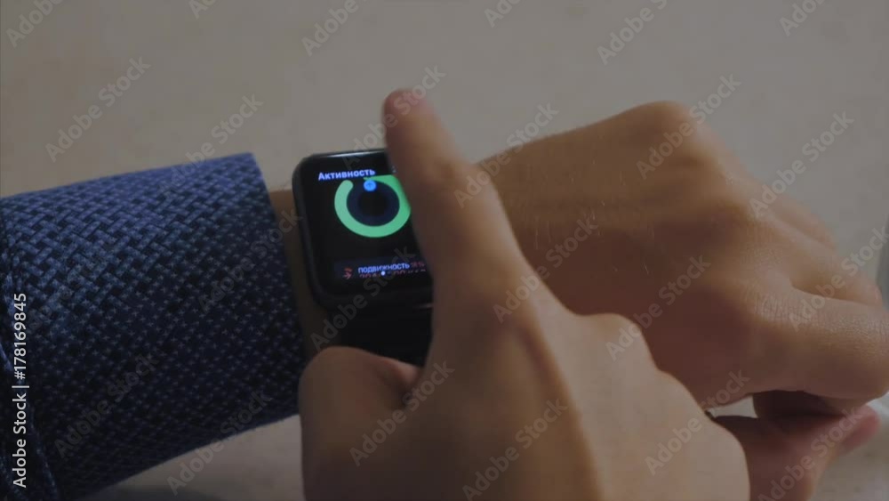 Poster man hand in watch with program on the screen against the background of table. man hand at the home w