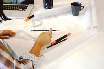 Designers hands working Interior Architecture drawings with plan on office supplies equipment and blueprint.