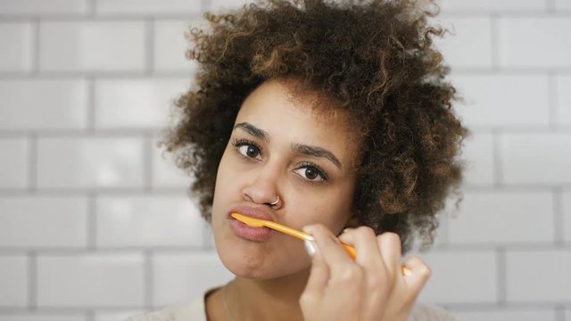 Attractive young woman pov of brushing teeth in the mirror to camera