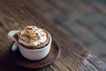 Cups of chocolate pudding with whipped cream on wooden background.