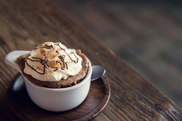 Cups of chocolate pudding with whipped cream on wooden background.