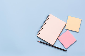 top view of blank notebook pencil and notice sticker on light blue background with copy space. memo and planning concept.