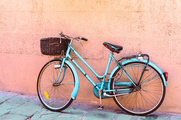 Fototapeta na wymiar old turquoise bicycle with basket parked near the wall, vintage toned