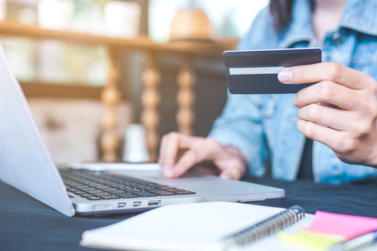 Woman hand holds a credit card and uses  a  laptop computer to shop online.