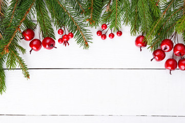 Fototapeta na wymiar New Year's, Christmas theme. Green fir branches, decorative berries on white wooden background. Celebratory background. Free space for inscriptions, notes.