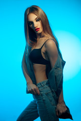 fashion model in jeans clothes with red lips looking away on blue background