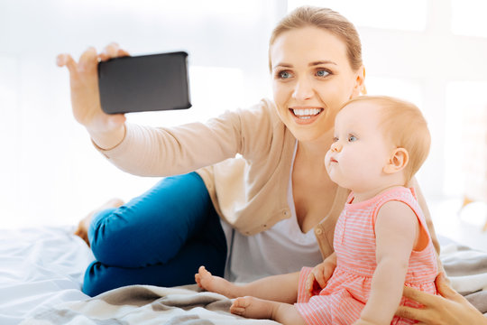 Delighted woman taking photos with her daughter