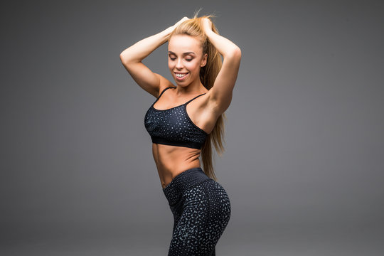 Fit beautiful and young athletic woman standing in a relaxed pose, big smile and wearing a grey and black sports outfit