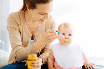 Pleasant young woman feeding a cute baby