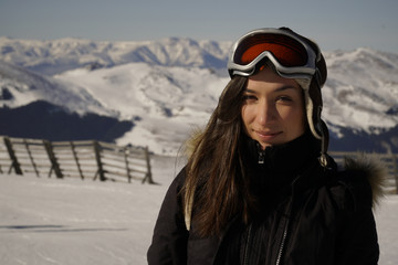 Fototapeta na wymiar Winter, ski - woman enjoying winter on ski vacation. Happy young woman in winter clothes posing against a mountain snow peak