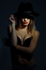portrait of young girl in black bra with red lips wearing a hat with wide brim in studio