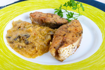 Roasted carp steaks with mushroom sauce on a plate on a white wooden background. Top view. Dish from the river fish.