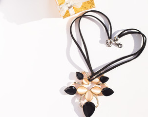 A black necklace forming shape of heart with golden jewelry box