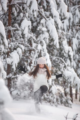 Happy woman on the winter background. Young pretty girl in the woods outdoors. Portrait of a cheerful beautiful woman.