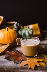 Hot coffee on rustic table with pumpkins and leaves. Autumn style.