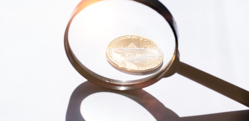 A magnifying glass and golden bitcoin with light leaks