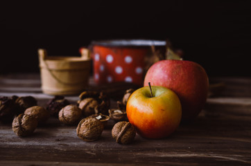 Walnuts and apples on rustic table with old details on it. Autumn style.