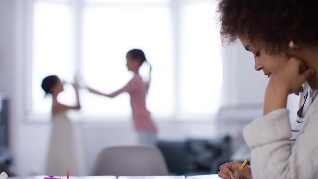 Young mother or childminder working whilst kids play in the background