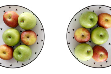 Top view of Red and green apples in white plate with black triangles pattern on the left and right side with white background.