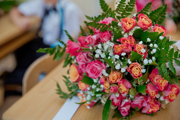 Stylish bouquet of red roses and red ribbon in a circular black box near pink gift bag. Valentines and anniversary concept