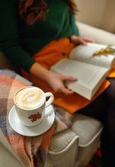 Cup of cappuccino and girl reading a book