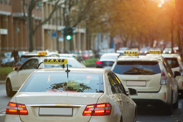 Taxi cars on the city street.  Cars parked at the side of the road.