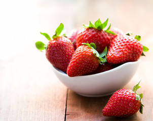 Fresh strawberries in a bowl on wooden table