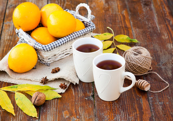 tea with lemon, honey, oranges, autumn leaves on woodenbackground