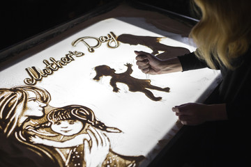 The woman draws on sand animation for mother's day