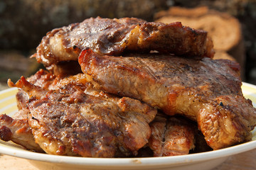 Close up view of juicy pork steak cooked on an open flame grill on big white plate..