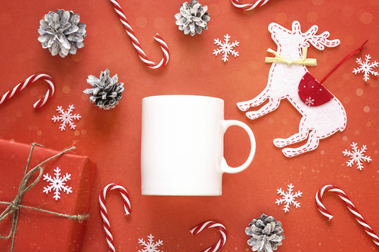 White coffee mug  with Christmas decorations on red background. Space for text or design.