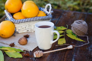 tea with lemon, honey, oranges, autumn leaves on woodenbackground