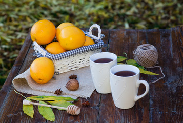 tea with lemon, honey, oranges, autumn leaves on woodenbackground