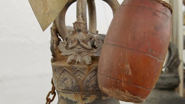 Mallet and decorative figure on sacral gong (bell) in Wat Saket Ratcha Wora Maha Wihan (the Golden Mount). Bangkok, Thailand.
