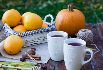 Obraz na płótnie Canvas tea with lemon, honey, oranges, autumn leaves on woodenbackground