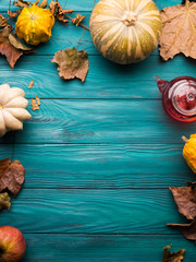 Moody green autumn background with pumpkin, apples, yellow leaves. Fall still life flat lay. Copy space frame