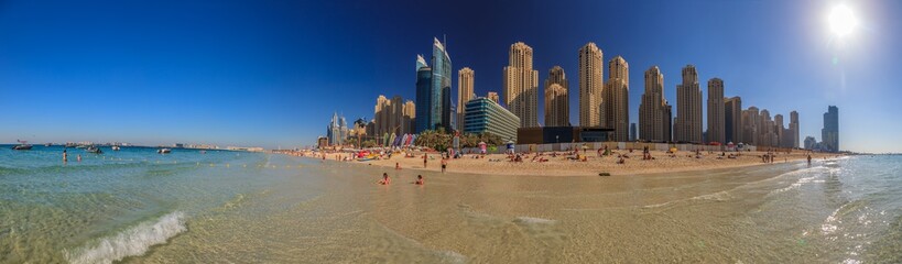 Panorama in Dubai vom Stadtstrand im Stadtteil Marina aus dem Wasser haraus mit Sonne und Skyline...