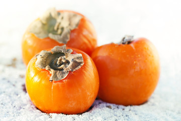 Delicious persimmons on white snow