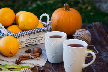tea with lemon, honey, oranges, autumn leaves on woodenbackground