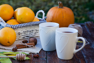 tea with lemon, honey, oranges, autumn leaves on woodenbackground