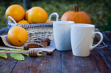 tea with lemon, honey, oranges, autumn leaves on woodenbackground