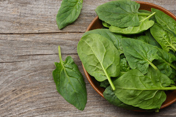 spinach leaves in bowl on old wooden table top view