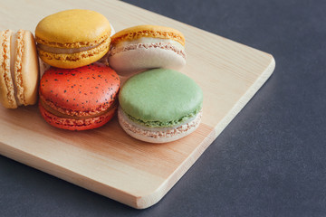 Colorful French macaron or Italian macaron stack on cutting board. Homemade delicious macaron on granite table with copy space for background or wallpaper. French dessert for served with tea or coffee