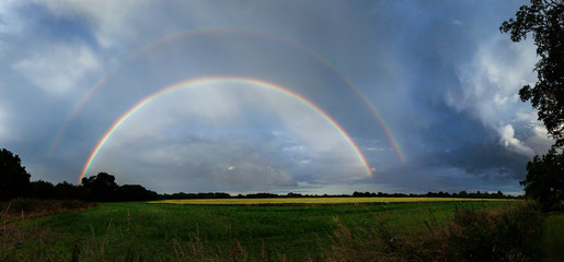 Full Double Rainbow in stormy sky with fields in foreground