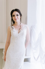 Beautiful bride perfect style. Wedding hairstyle make-up dress and bride's bouquet. Young attractive bride near window in white room at studio