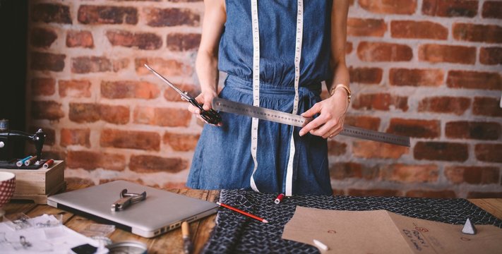 Young female fashion designer holding tools in her hands