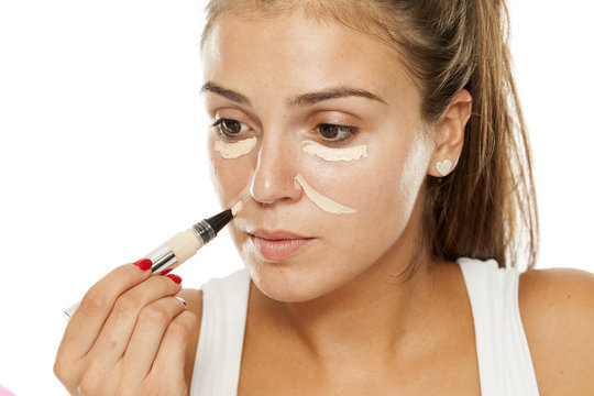 young women applied concealer under the eyes and nose, with applicator