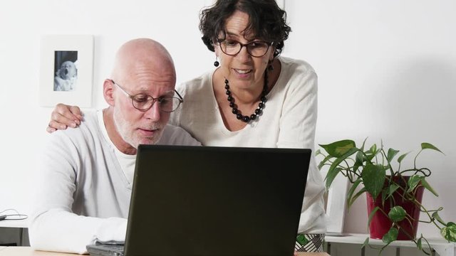 Senior couple at home using laptop computer